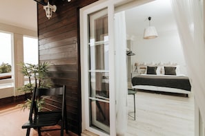 A bedroom with a bed, a bedside table, a hanging light fixture, and a window with curtains. - O House Ericeira Hills (Mafra)