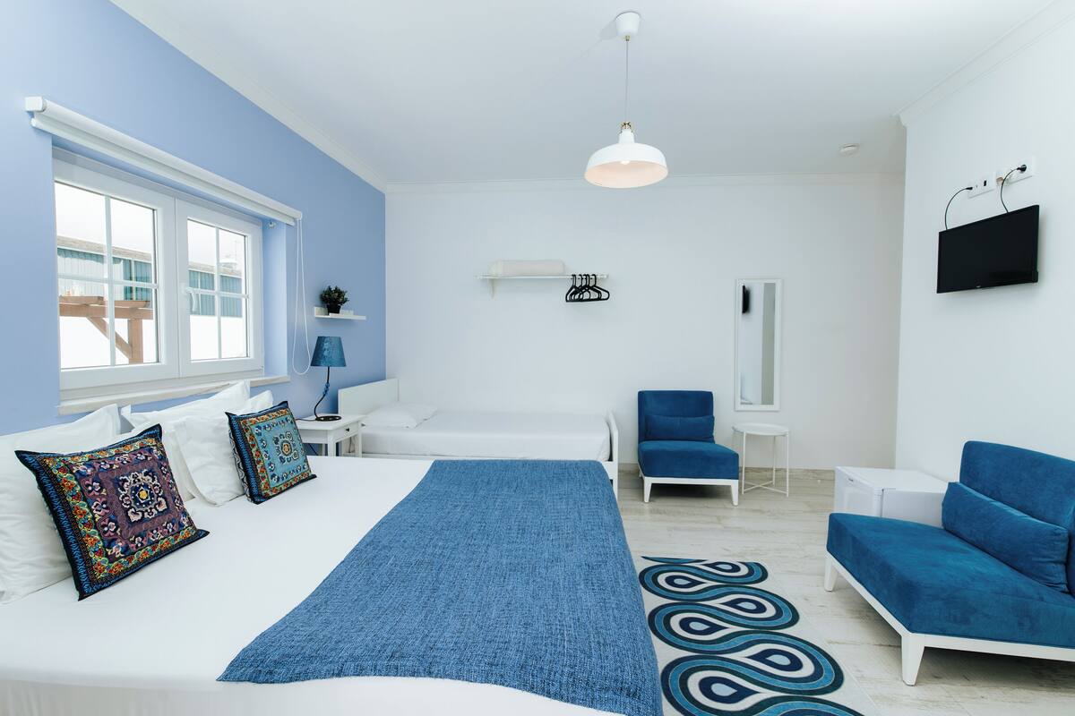 Una camera da letto moderna con un grande letto, una parete di colore blu, una televisione e un’area relax.