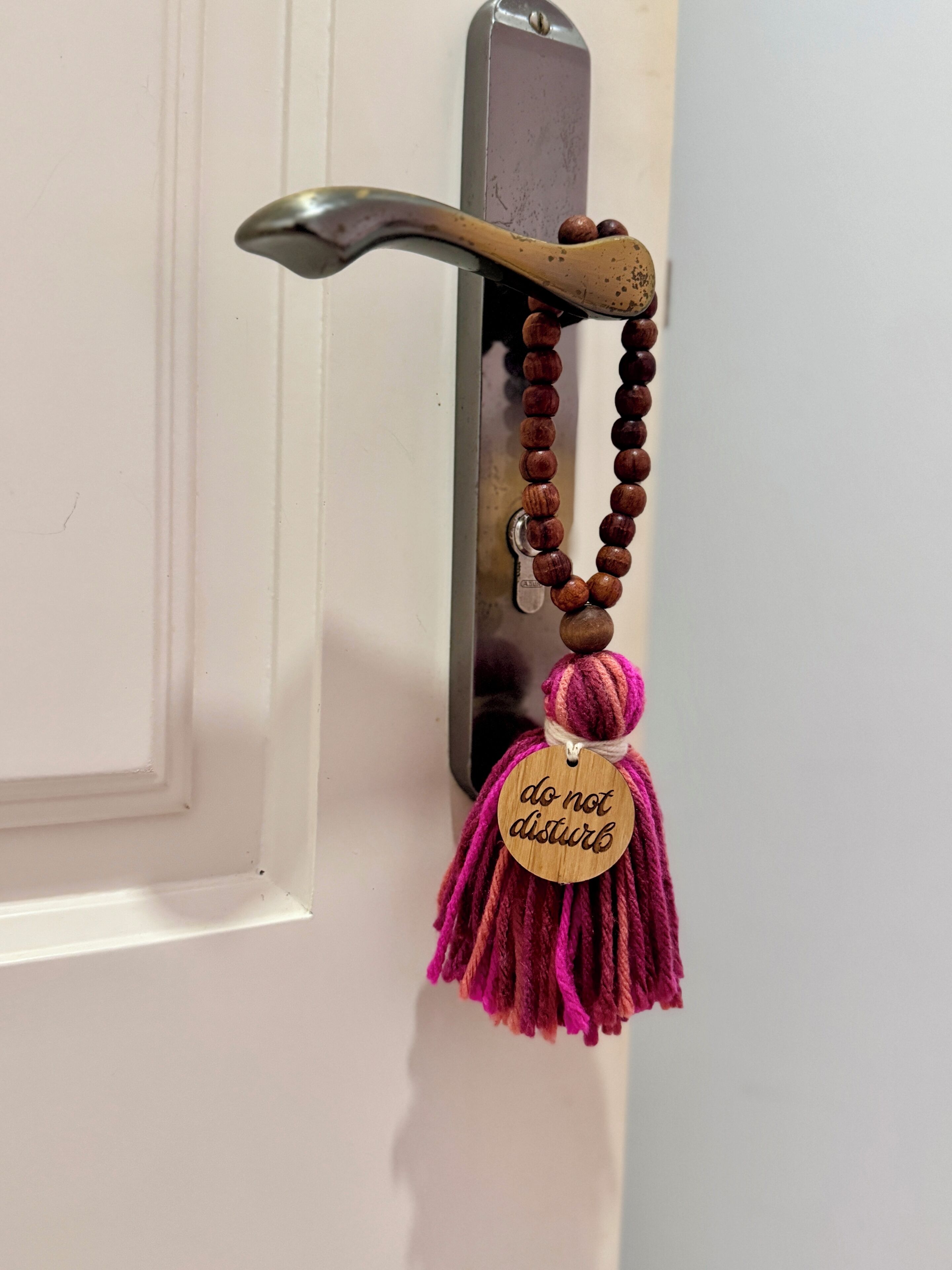 Uma porta com maçaneta e chaveiro de madeira com a inscrição 'não perturbe'.