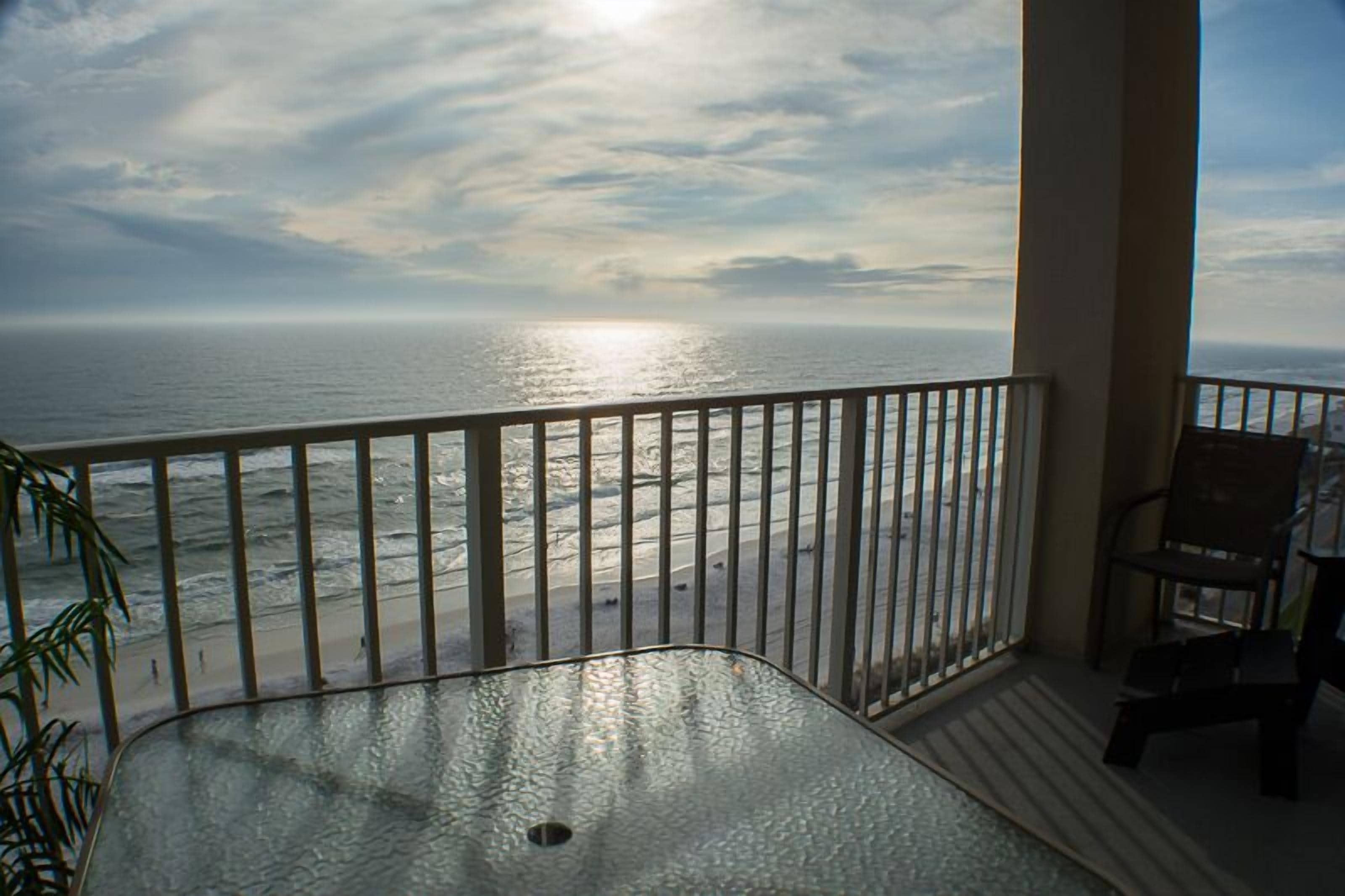A balcony with a view of the ocean and a chair.