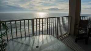 A balcony with a view of the ocean and a chair.