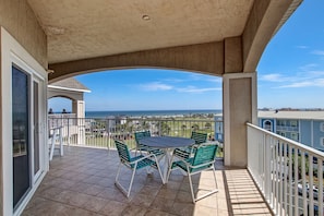 Enjoy the ocean view from this balcony with a table and chairs.