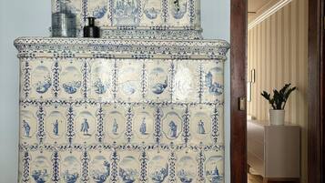 Un buffet traditionnel aux carreaux bleus et blancs, surmonté d’un élément décoratif, placé dans une pièce dotée d’une porte en bois et donnant sur une autre pièce.