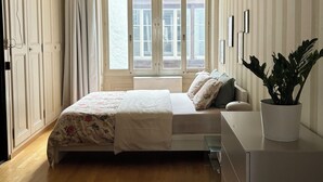 A bedroom with a bed, a potted plant, a dresser, and a window with curtains. - Bright & Stylish •  Heart of Old City •  Great Design (Berne)