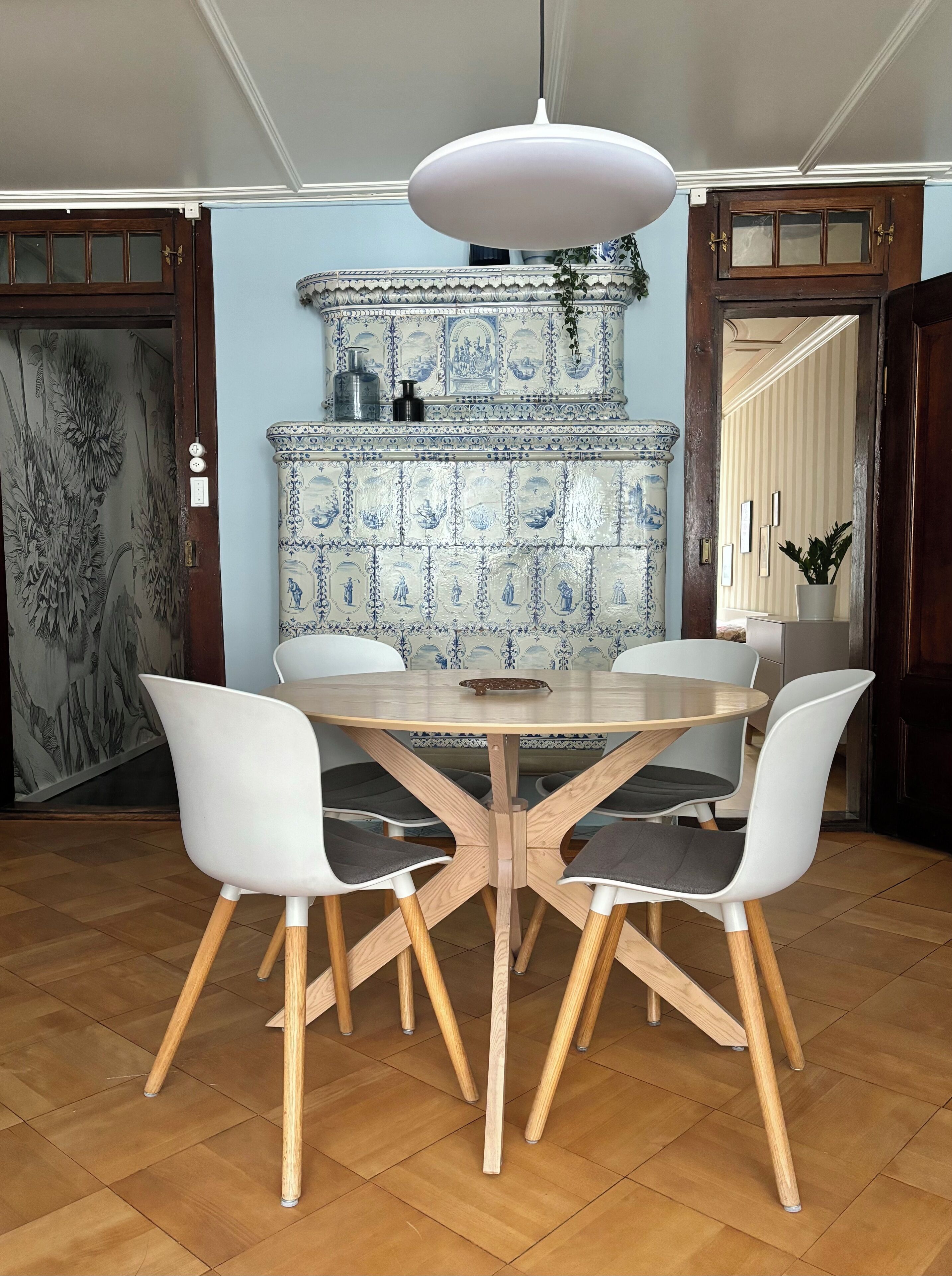 A dining area with a round table and four chairs, a decorative tile wall, and a hanging light fixture.