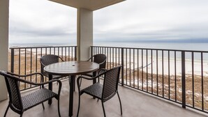 A balcony with a round table and four chairs, overlooking a beach with a railing. - Phoenix VI 1002 by Liquid Life (Orange Beach)