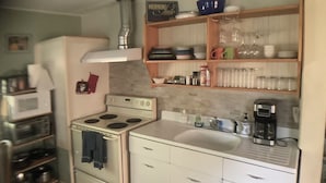 Une cuisine compacte équipée d’une cuisinière, d’un four, d’un four à micro-ondes et d’une machine à café.