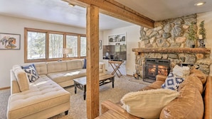 A cozy living room with a stone fireplace, a large sofa, and a television. - Large home on 5 acres, 5 bedrooms, 3 bathrooms and sleeps up to 14 people (Fraser)