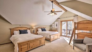 A bedroom with two wooden beds, a ceiling fan, a wooden bench, and a view of the outdoors. - Large home on 5 acres, 5 bedrooms, 3 bathrooms and sleeps up to 14 people (Fraser)
