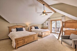 Ein Schlafzimmer mit zwei Holzbetten, einem Deckenventilator, einer Holzbank und Blick ins Freie.