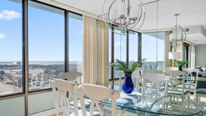 Ein modernes Hotelzimmer mit einem großen Glastisch, weißen Stühlen und Blick auf die Stadt.