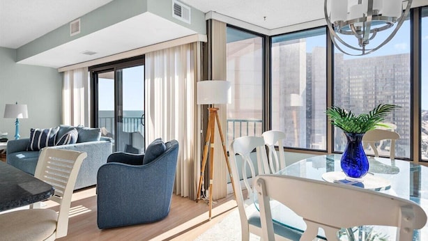 Ein modernes Hotelzimmer mit Balkon, Essbereich und Blick auf die Stadt.