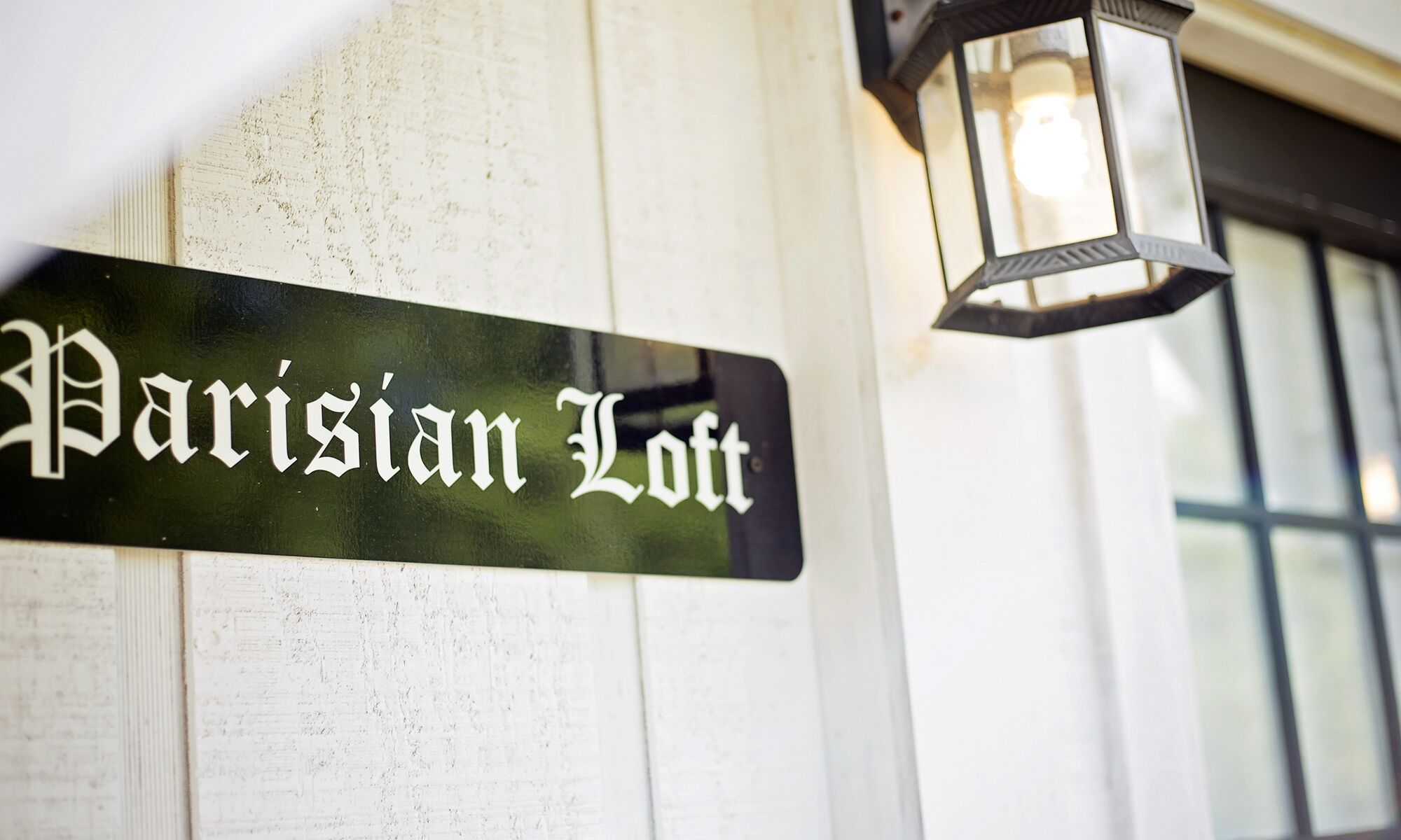 Een straatnaambordje met de tekst 'Parisian Loft' bevestigd aan een gebouw.