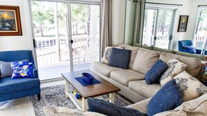 Un salon avec un canapé beige, un fauteuil bleu, une table basse en bois et un tapis à motifs.