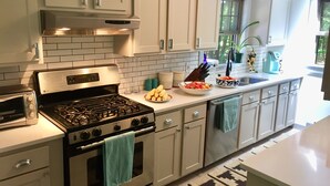 A modern kitchen with white cabinets, a stainless steel stove, and a built-in oven. There is a window providing natural light and a view of greenery outside. - <br>Escape to our incredibly private home on 30 acres! (Saugerties)