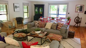A cozy living room with a grey sofa, a wooden coffee table, and a red chair. - <br>Escape to our incredibly private home on 30 acres! (Saugerties)