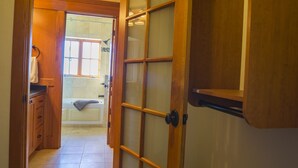 A hallway leading to a bathroom with a bathtub, wooden cabinets, and a tiled floor. - FisherBros flats 203 (Astoria)