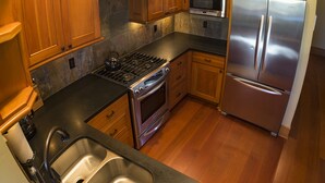 A modern kitchen with wooden cabinets, stainless steel appliances, and a black countertop. - FisherBros flats 203 (Astoria)