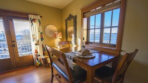 A dining area with a wooden table, chairs, a window with a view, and a door leading outside. - FisherBros flats 203 (Astoria)