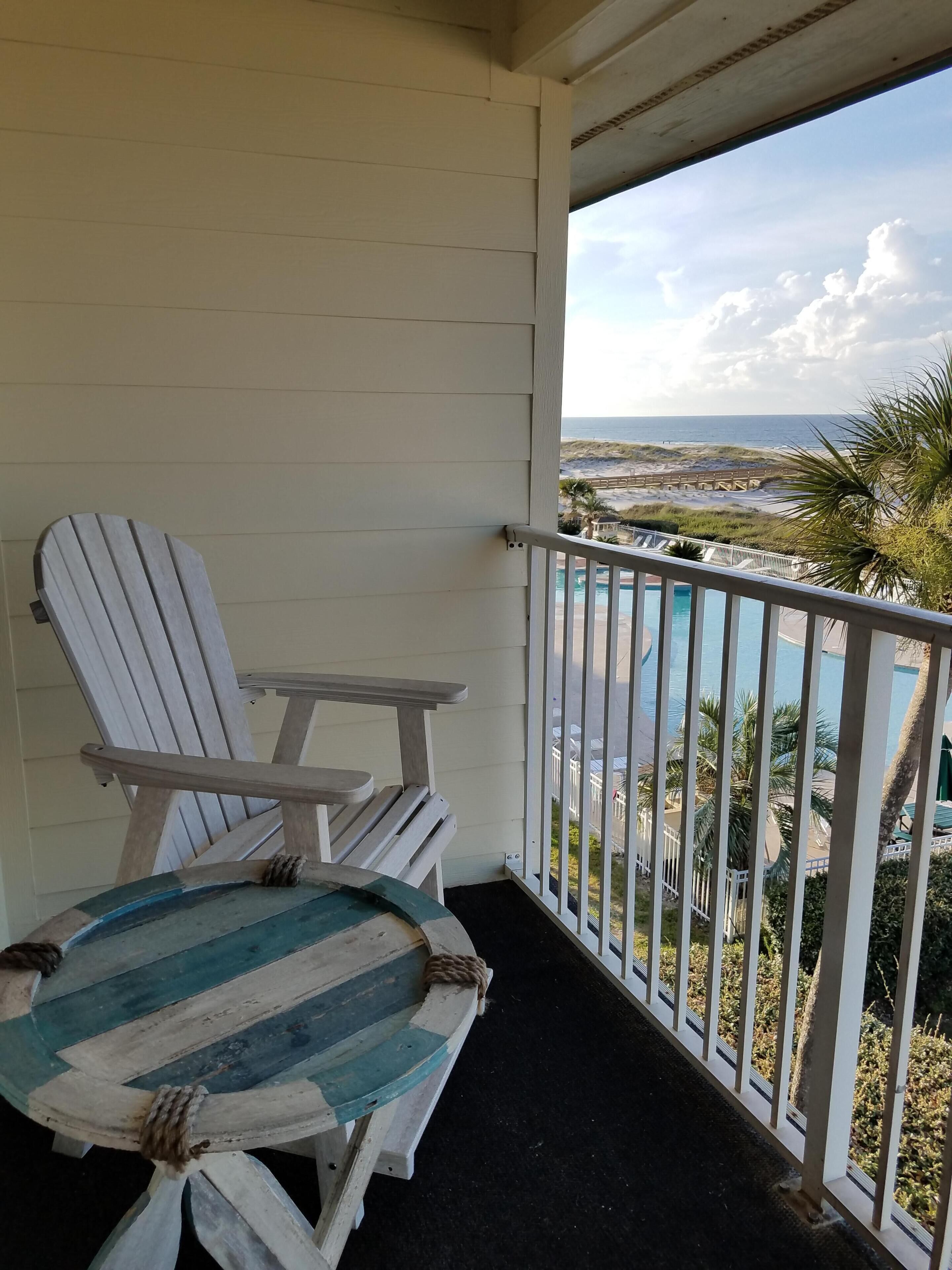 A balcony with a view of the beach and a pool.