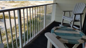 Ein Balkon mit Blick auf den Strand, einer Fischdeko und zwei Adirondack-Stühlen.