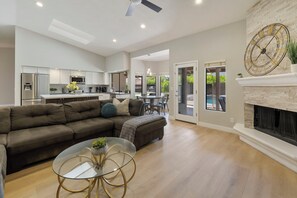 A spacious living room with a sectional sofa, a glass coffee table, and a fireplace. - Luxury Home w/ NEW back yard and Heated Pool (Scottsdale)