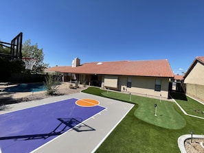 A residential area with a basketball court, a swimming pool, and a house with a red-tiled roof. - Luxury Home w/ NEW back yard and Heated Pool (Scottsdale)