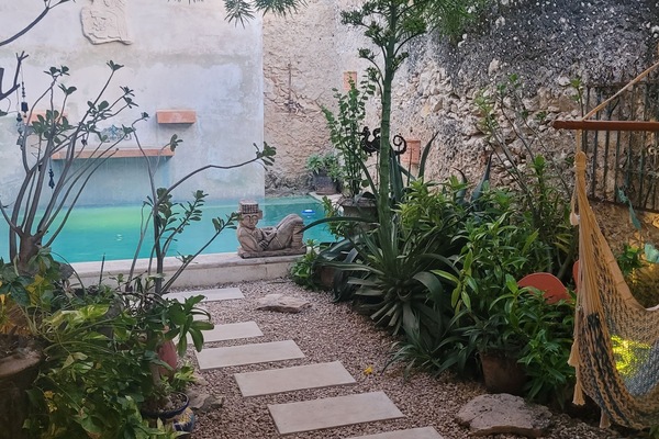 View of the pool from the covered patio area. Chaac Mool, hammock chair.