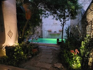 Ein Innenhof mit kleinem Pool, Steinweg und unterschiedlicher Bepflanzung.