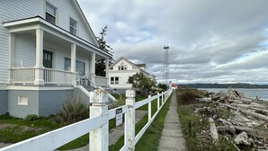A coastal property with a white fence, a paved walkway, and a view of the sea. - Point Robinson Lighthouse - Keeper's Quarters B (Vashon Island)