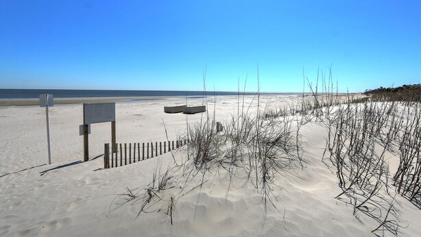 A sandy beach with a wooden fence and a signpost. - Walk to beach, indoor/outdoor pools, washer/dryer (Hilton Head Island)