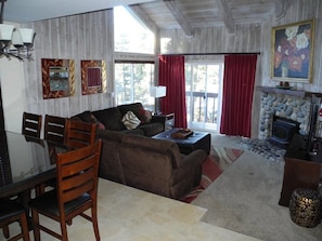 Una sala de estar acogedora con chimenea, un sofá, una mesa de centro y una zona de comedor con sillas y una mesa.