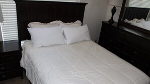 A bed with white bedding, a dark headboard, and a dresser with drawers. - Courchevel 27 (Mammoth Lakes)