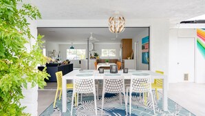Un comedor moderno con una mesa blanca, sillas amarillas y una alfombra estampada.