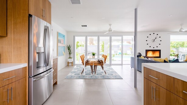 Una cocina moderna con armarios de madera, un refrigerador de acero inoxidable y un comedor con mesa y sillas.