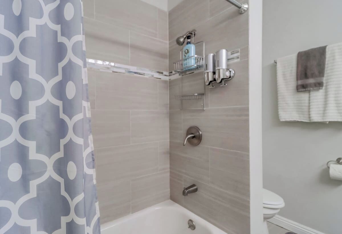 A bathroom with a shower, toilet, and a towel rack.