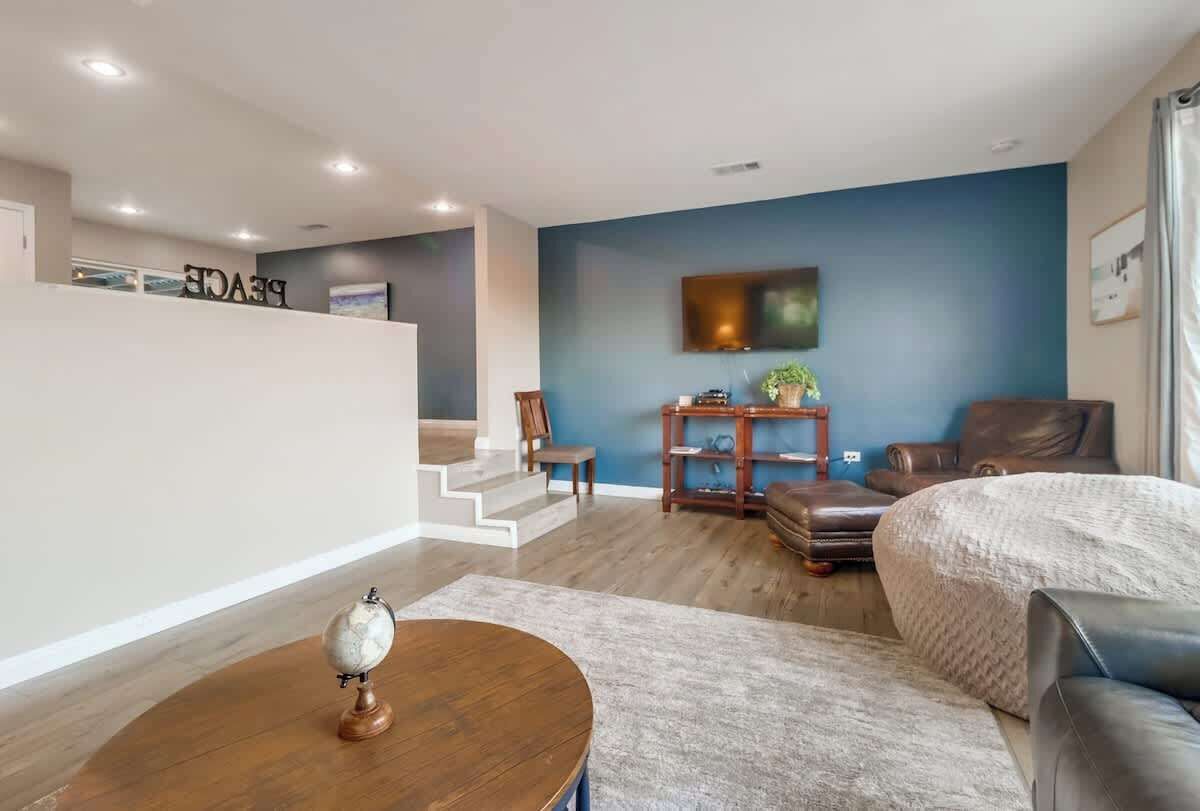 A modern living room with a blue accent wall, a flat-screen TV, leather furniture, and a globe on a wooden table.
