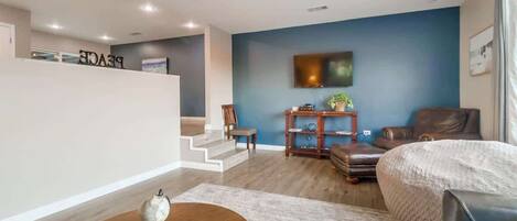 A modern living room with a blue accent wall, a flat-screen TV, leather furniture, and a globe on a wooden table.
