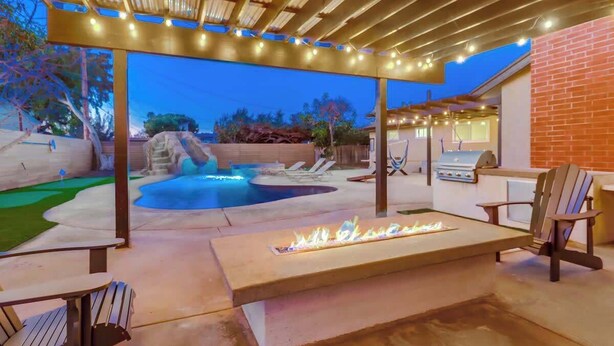 An outdoor patio with a fire feature, seating, and a pool area. - Salt Water Pool & Mini Golf - Close to Downtown (Bonita)
