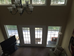 A living room with a TV, a chandelier, and a view of a gated driveway. - Secluded Seneca/Clemson Lake Hartwell Waterfront, 3 miles to CU (Seneca)