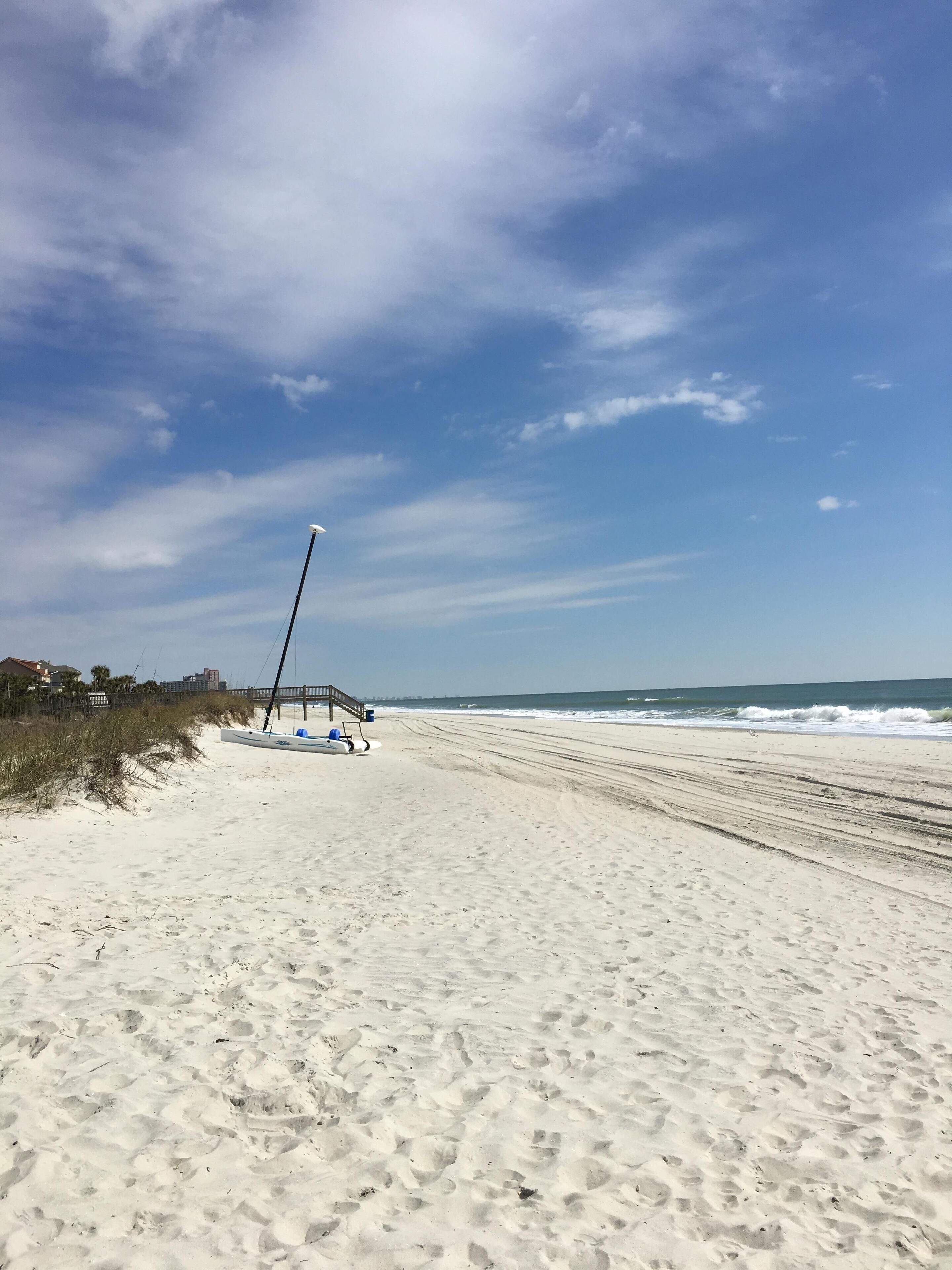 Una playa con arena, una torre de salvavidas y un muelle que se adentra en el océano.