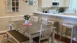Un comedor con una mesa de madera, sillas, una araña y un tapete estampado.