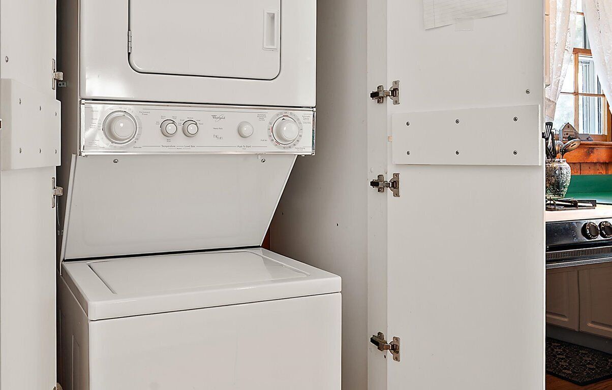 A compact kitchen with a white stove, a white washing machine, and a cabinet with a lock.