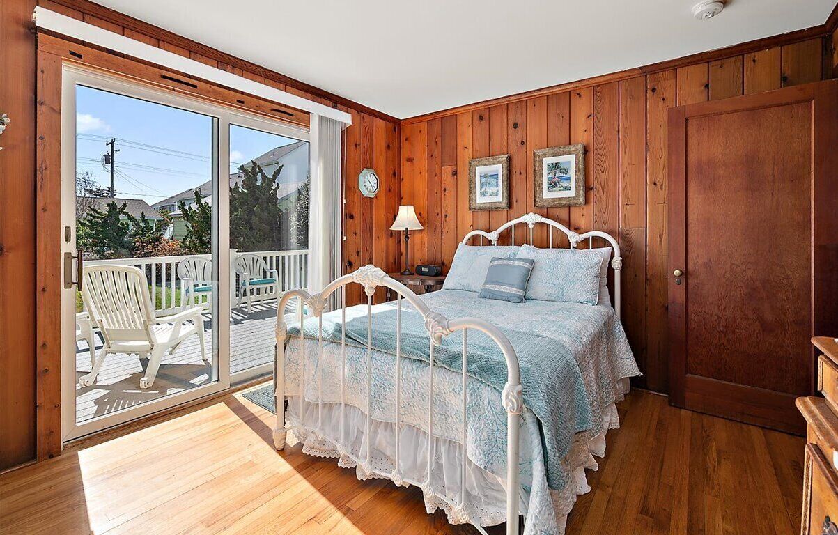 Un dormitorio con una cama, una mesita de noche, una lámpara y una puerta de madera.