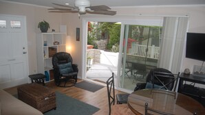 A living room with a sofa, a glass-top dining table, and a ceiling fan. - Beach Cottage - 4th from Ocean, Private Patio, Ocean View, now with A/C (San Diego)