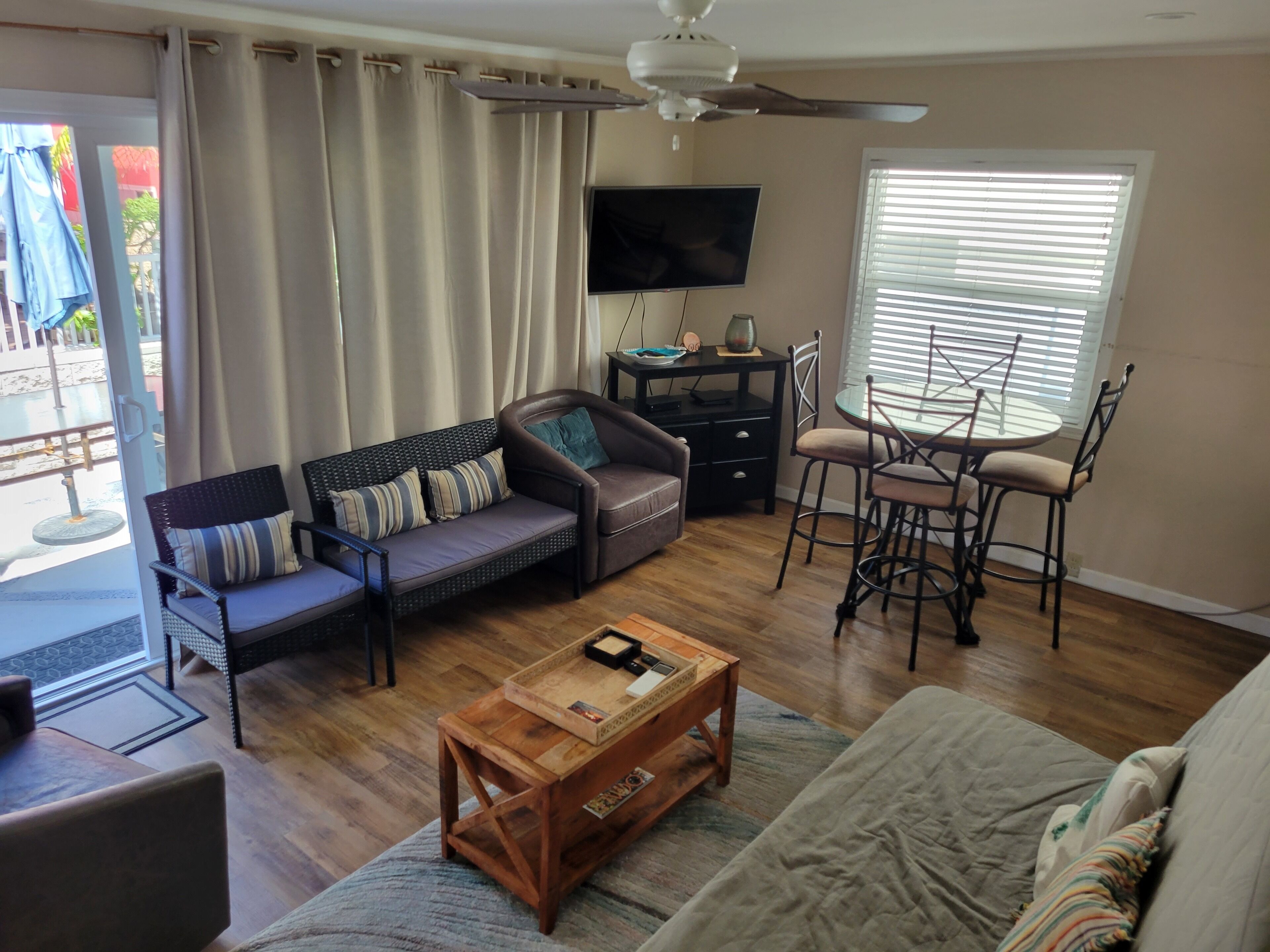 A living room with a sofa, a coffee table, a TV, and a dining area with chairs and a table.