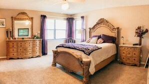 Ein Schlafzimmer mit einem großen Bett, einem Schminktisch, einem Frisiertisch und einem Deckenventilator.