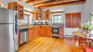 Una cocina con armarios de madera, un refrigerador de acero inoxidable y un comedor de madera con un jarrón de flores.