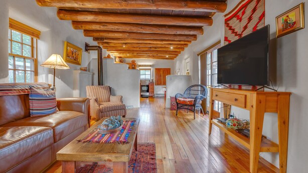 Una sala de estar acogedora con techo de madera, sofá de cuero y un televisor sobre un mueble de madera.