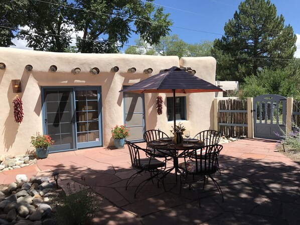 A patio with a table and chairs, a potted plant, and a decorative wall.